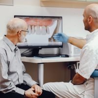Handsome old man talking to the dendist. Two man in the dentist's office