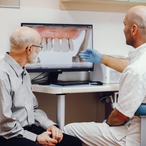 Handsome old man talking to the dendist. Two man in the dentist's office